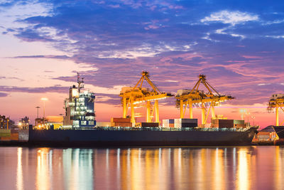 Cranes at commercial dock against sky