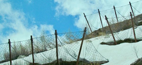 Low angle view of fence on field against sky