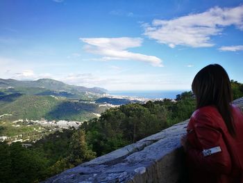 Rear view of woman standing on mountain against sky