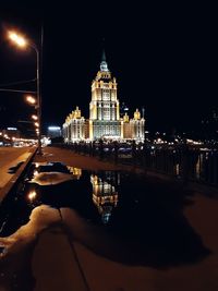 Illuminated buildings by river at night