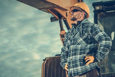 Man standing against earth mover at construction site