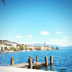 Scenic view of sea by town against blue sky