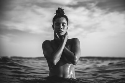 Shirtless woman in sea against sky during sunset