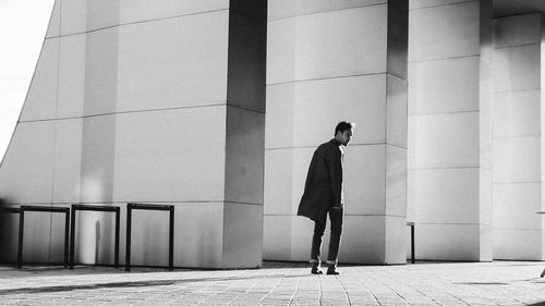 Full length side view of man walking on footpath against building