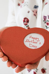 Midsection of woman holding red heart shape on mother day
