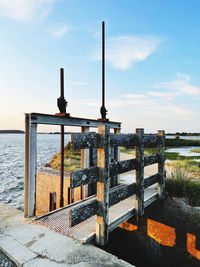 Wooden post by sea against sky