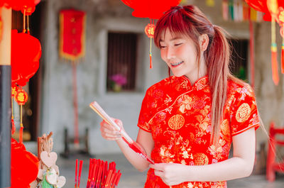 Young woman in traditional clothing holding incense