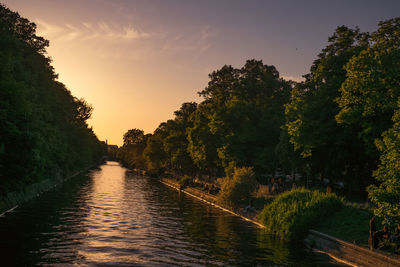 River amidst trees against sky during sunset