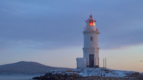 Lighthouse by sea against sky