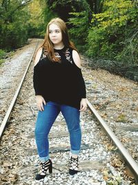 Teenage girl looking away while standing on railroad track