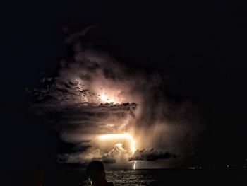 People in sea against sky at night