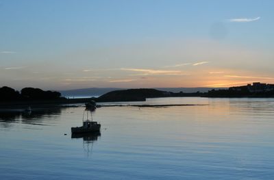 Silhouette boat in lake against sky at sunset