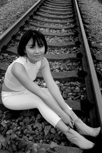 Portrait of woman sitting on railroad track