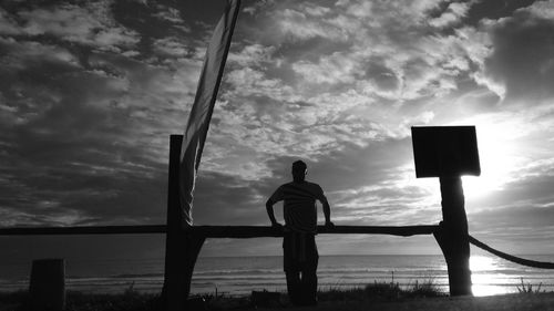 Silhouette of woman in sea against cloudy sky