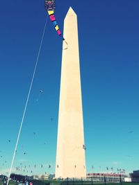 Low angle view of flags against clear blue sky