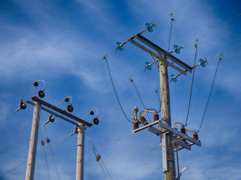 Low angle view of electricity pylon against blue sky