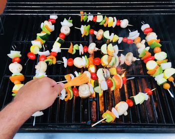 Cropped hand preparing food on barbecue grill