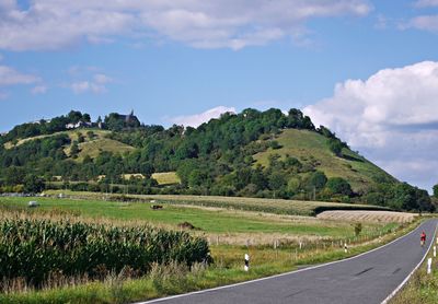 Road amidst green landscape against sky