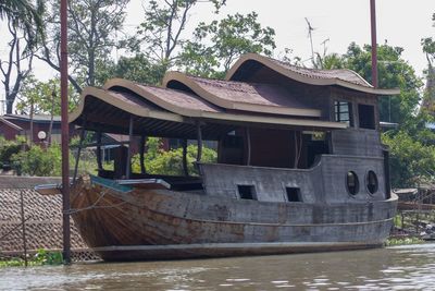 Abandoned house by river against sky