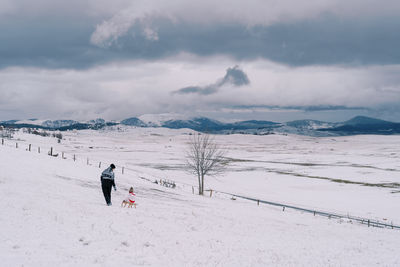 Rear view of man walking on snow covered landscape