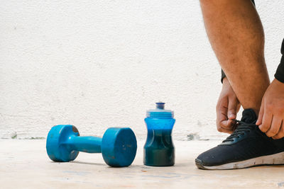 Low section of man lifting dumbbell in gym