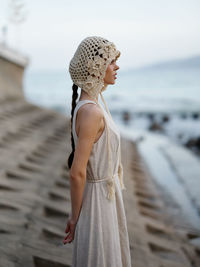 Side view of young woman standing at beach