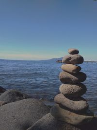 Stack of stones on beach against sky