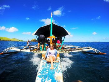 People on boat in sea against sky