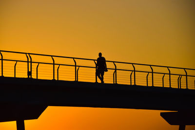 Low angle view of silhouette man on bridge against sky during sunset