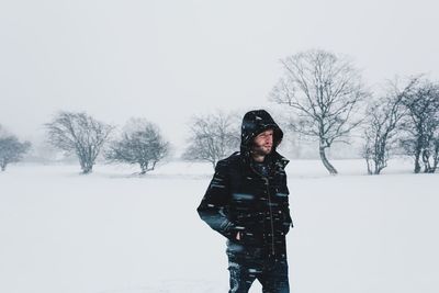 Woman standing on snow covered field against sky