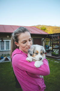 Girl holds smiling australian shepherd puppy. love and relationship between female dog and female