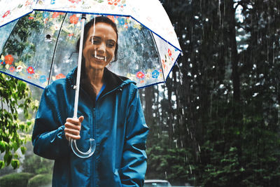 Portrait of woman holding wet umbrella during rainy season