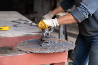Man bends metal part creating curved shape using special machine. blacksmith shop - metal workshop.
