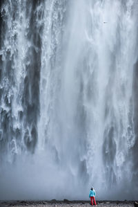 Rear view of person standing waterfall