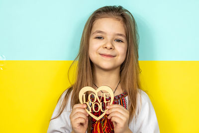 Portrait of smiling young woman standing against yellow wall