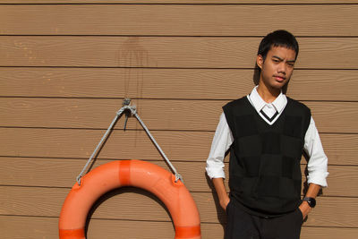 Portrait of young man standing against wall