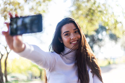 Close-up of smiling young woman taking selfie outdoors