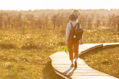 Naturalist woman botanist with backpack on ecological hiking trail in summer outdoors. 