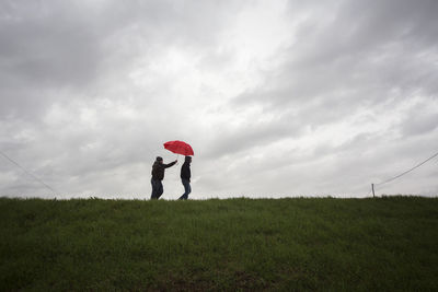 People standing on field against sky