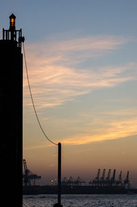 Silhouette bridge by sea against sky during sunset