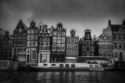 Buildings by river against sky