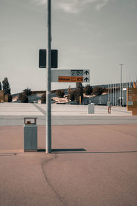 Road sign by street against sky in city