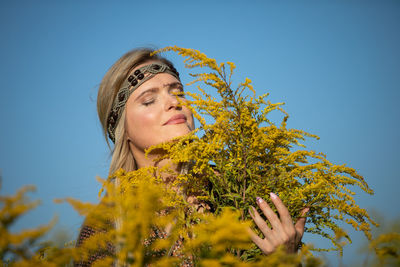 Low angle view of young woman against blue sky