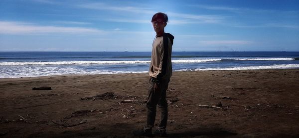 Man standing on beach by sea against sky