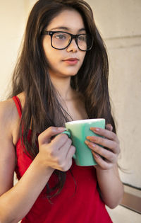 Young woman holding cup while looking away