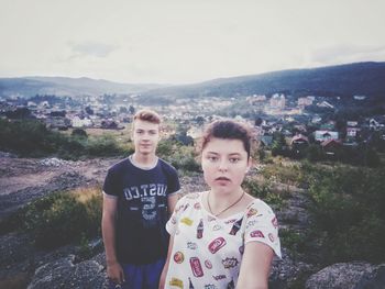 Portrait of friends standing on mountain in city against sky