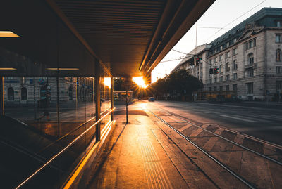 Illuminated street amidst buildings in city during sunset