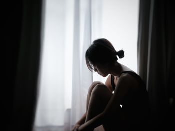 Side view of a young woman sitting at home