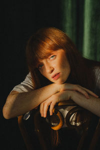 Young woman looking away while standing against black background