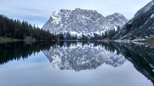 Reflection of trees in lake against snowcapped mountains